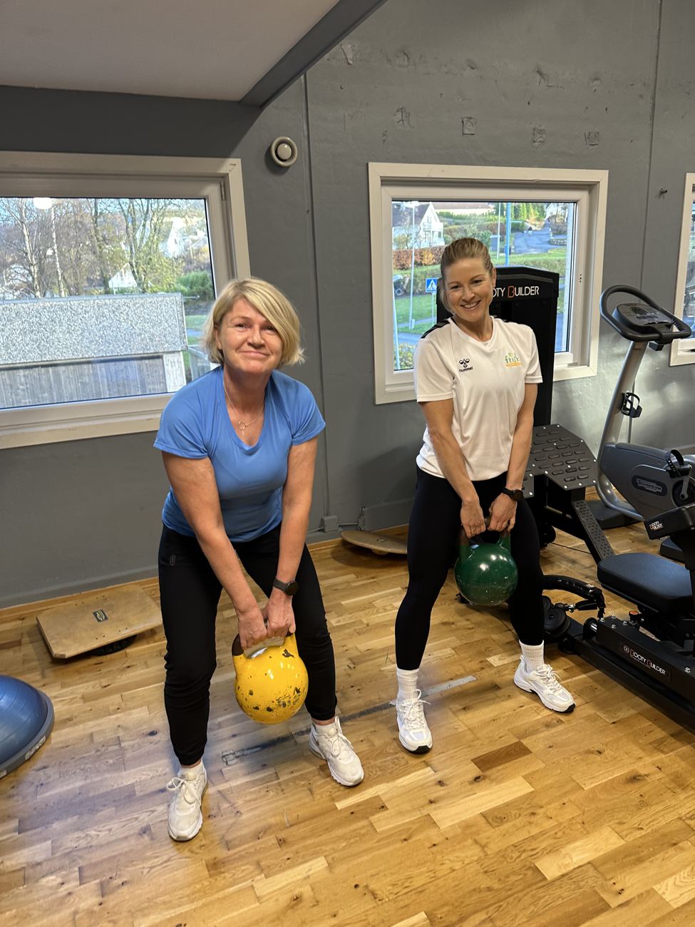 Medlem trener med kettlebell sammen med instruktør